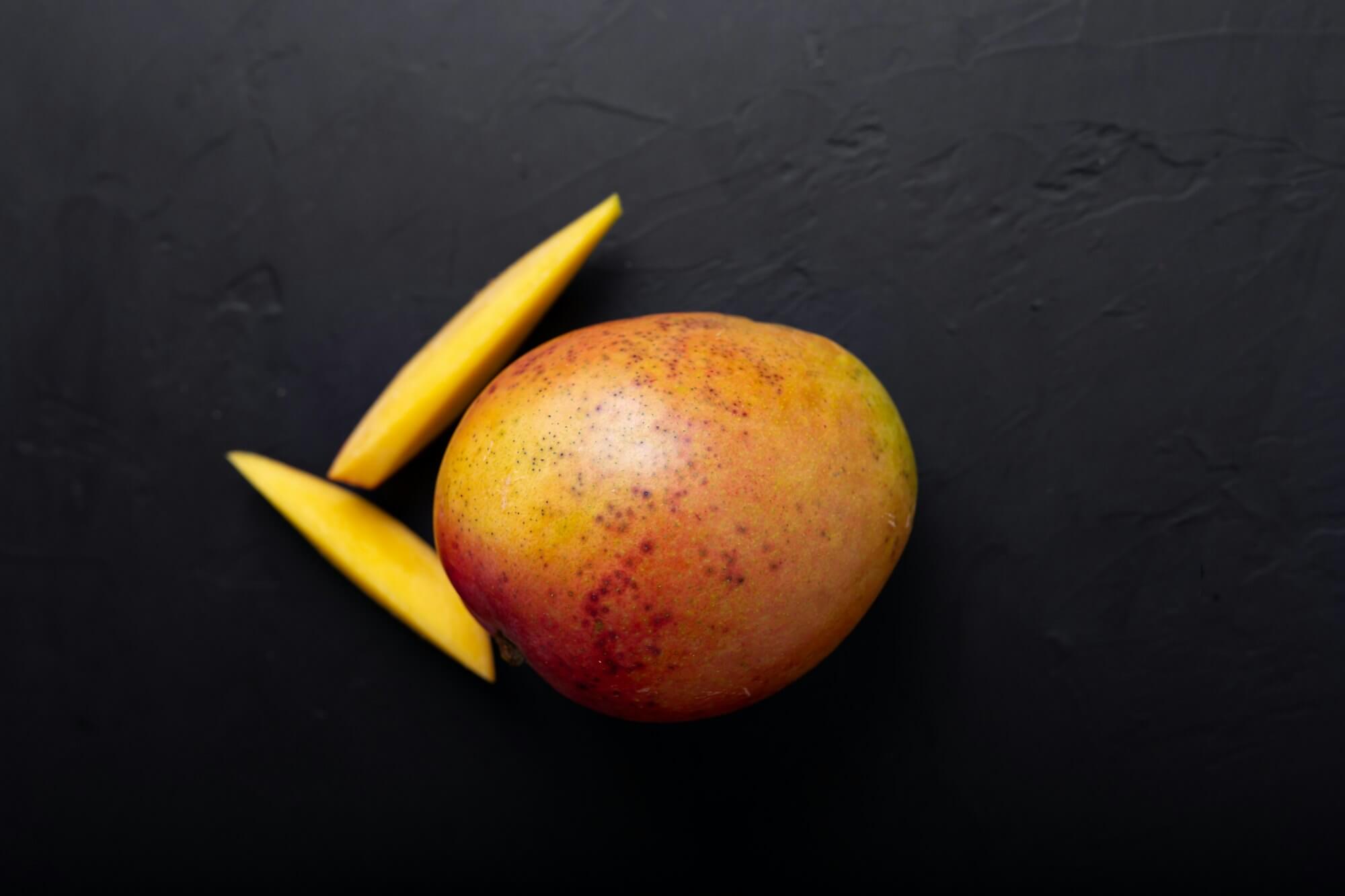 Beautiful summer nature background with mango fruit. Healthy dessert. Mango on black.