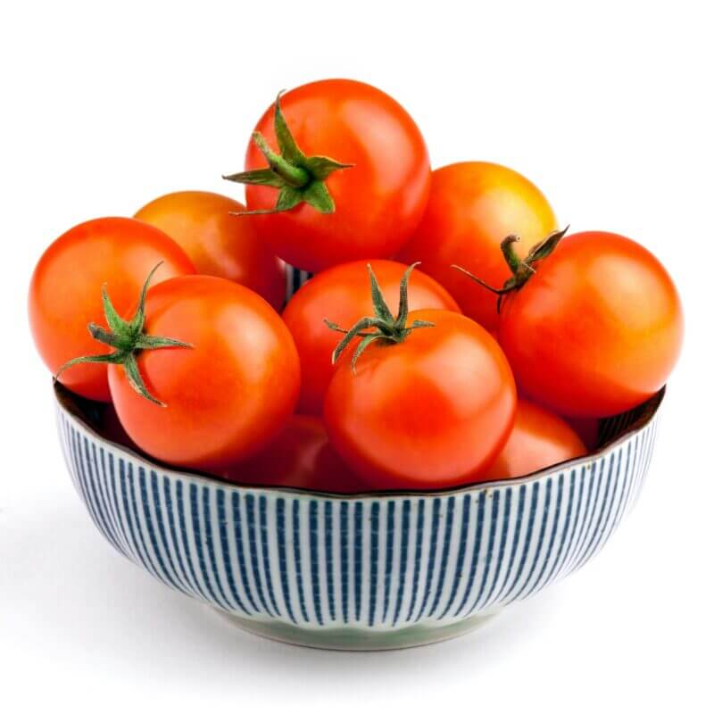 Bowl full of red tomato vegetables isolated on white background, front view closeup picture