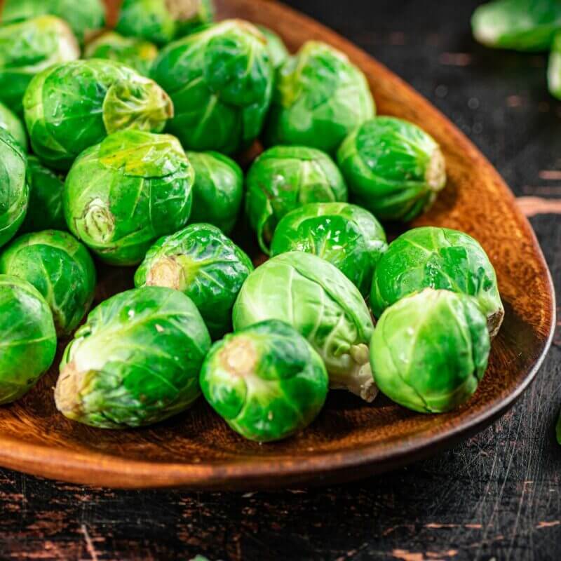 Fresh Brussel cabbage on a wooden plate.